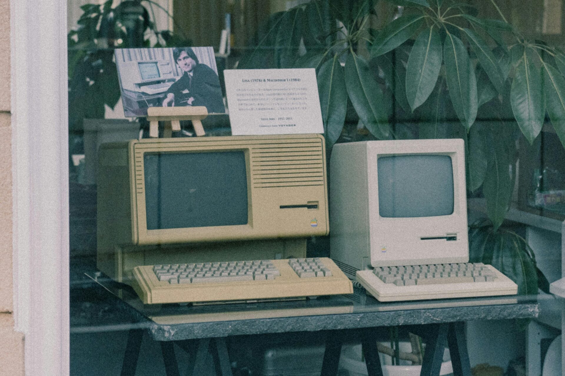 Retro-Apple-Computer mit Tastaturen stehen in einem Schaufenster in Tokio und zeigen frühes Technologiedesign.