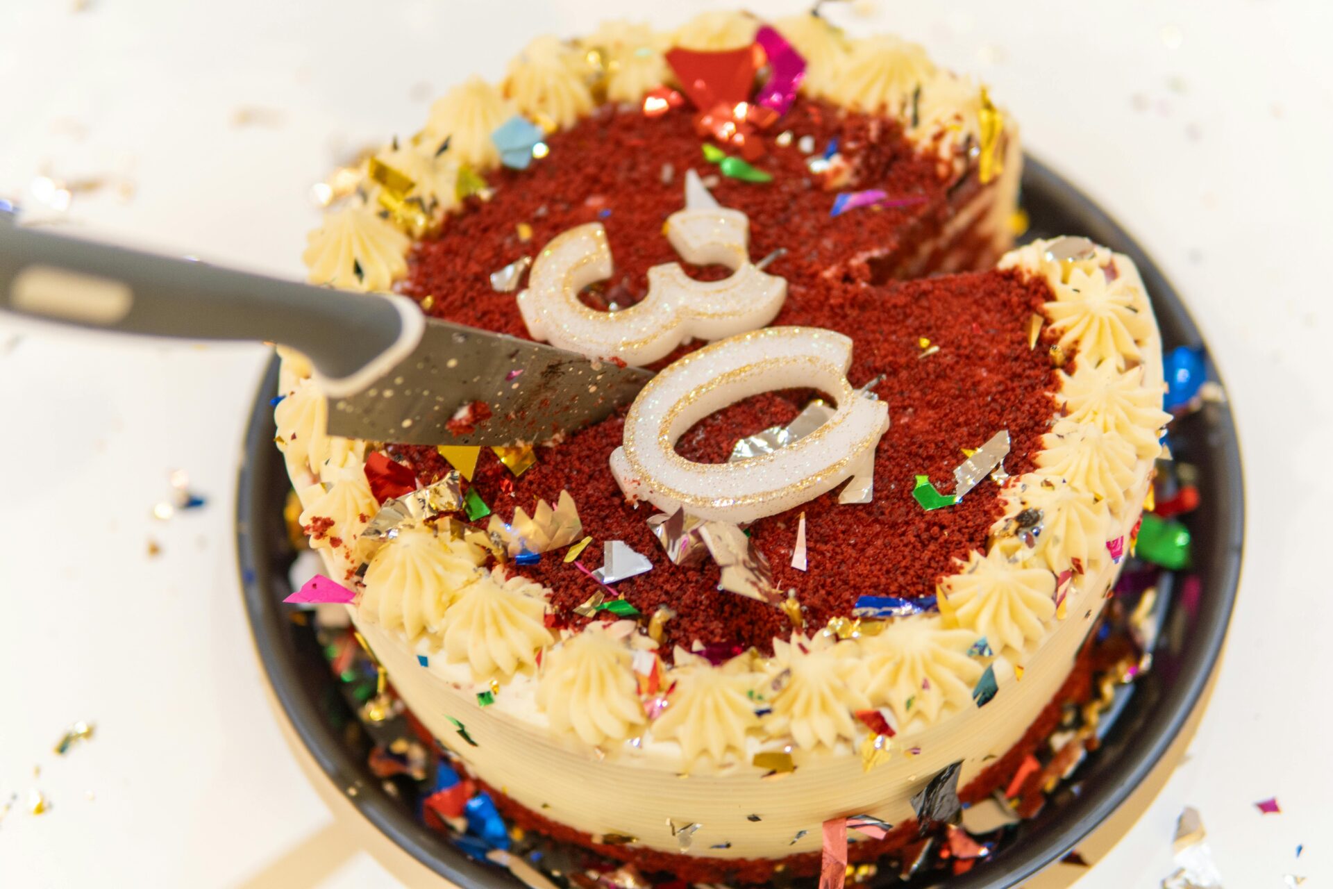 Lebendiger Red-Velvet-Kuchen mit Sahneglasur und bunten Kerzen, perfekt für eine Geburtstagsfeier.