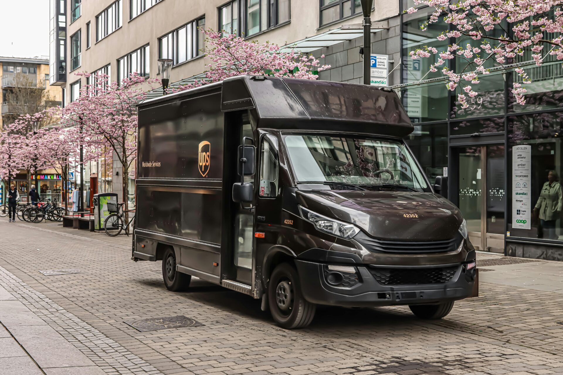 Schwarzer UPS-Lieferwagen parkt auf einer Stra&Atilde;Ÿe in J&Atilde;&para;nk&Atilde;&para;ping, Schweden, mit Kirschbl&Atilde;&frac14;ten im Fr&Atilde;&frac14;hling.