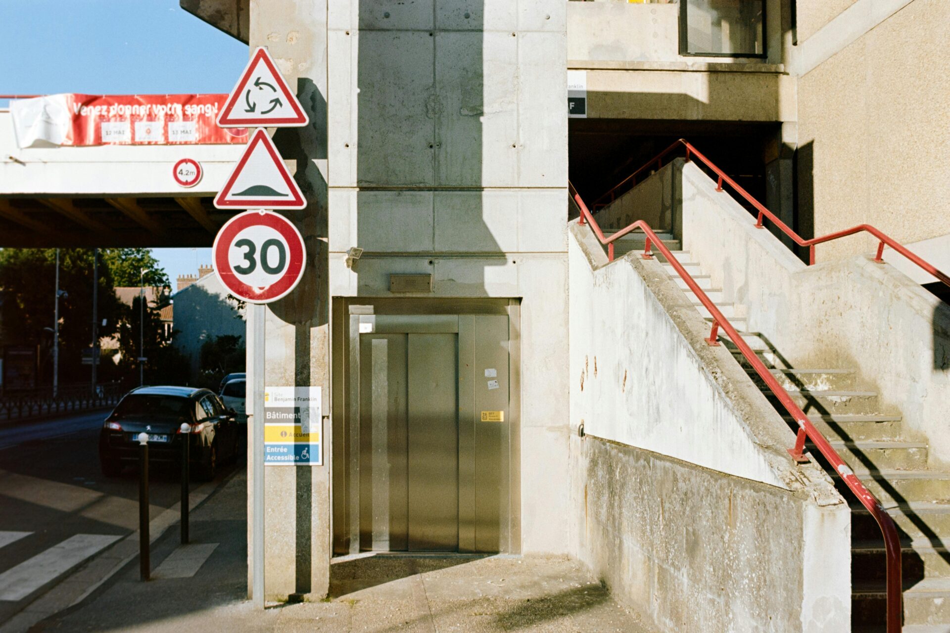 Stadtlandschaft mit einem Tempolimit-Schild, Betonstrukturen und geparkten Autos.