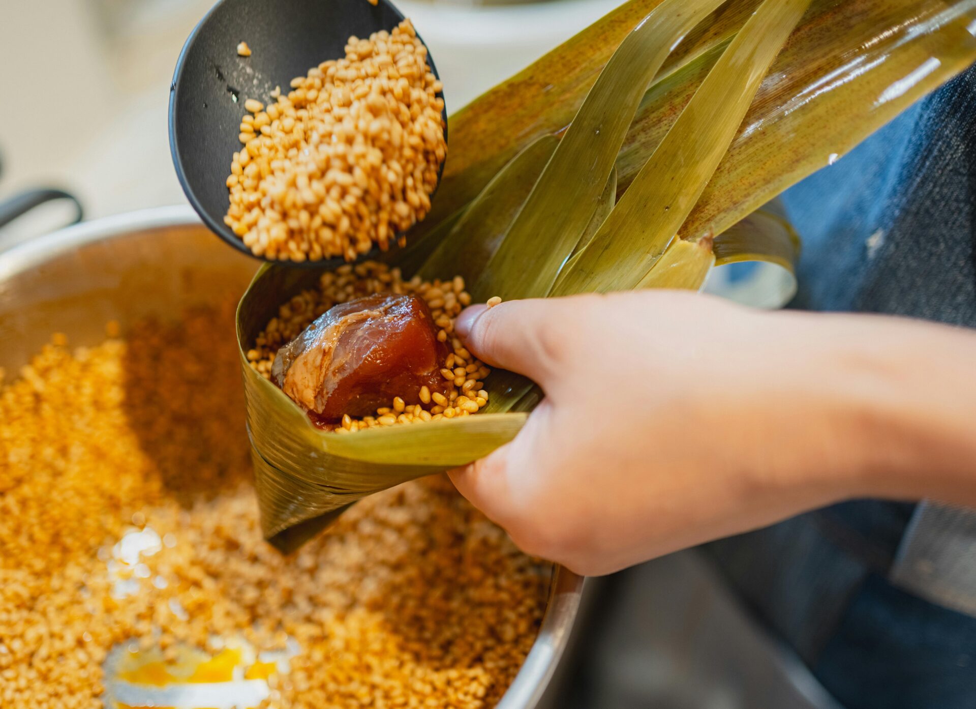 Eine Nahaufnahme einer Person, die in Tokio japanische Reiskn&Atilde;&para;del aus Bambusbl&Atilde;&curren;ttern zubereitet.