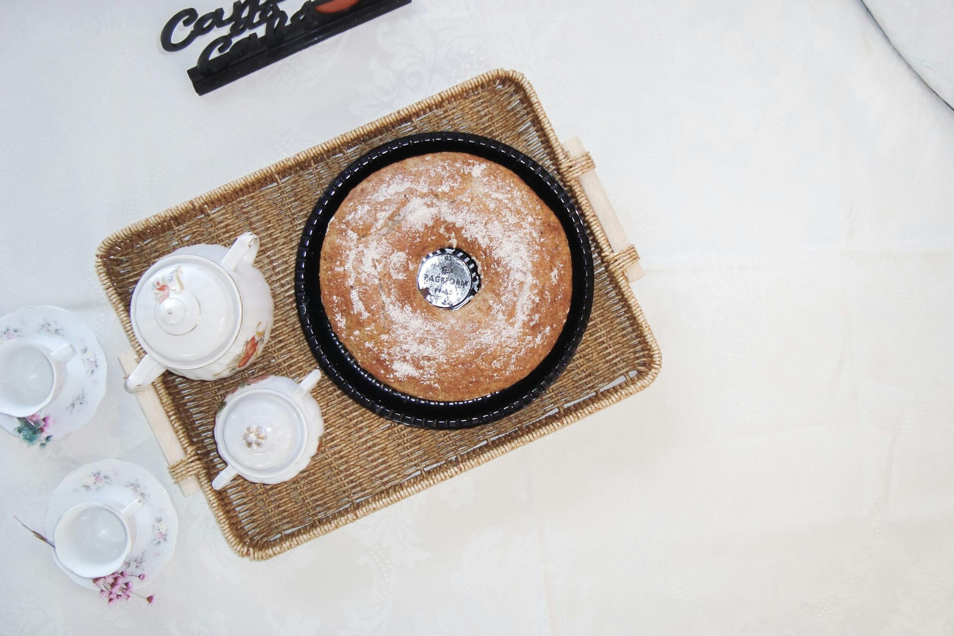 Draufsicht auf einen brasilianischen Kaffeekuchen mit Teeservice auf einem Korbtablett. Elegant und einladend.