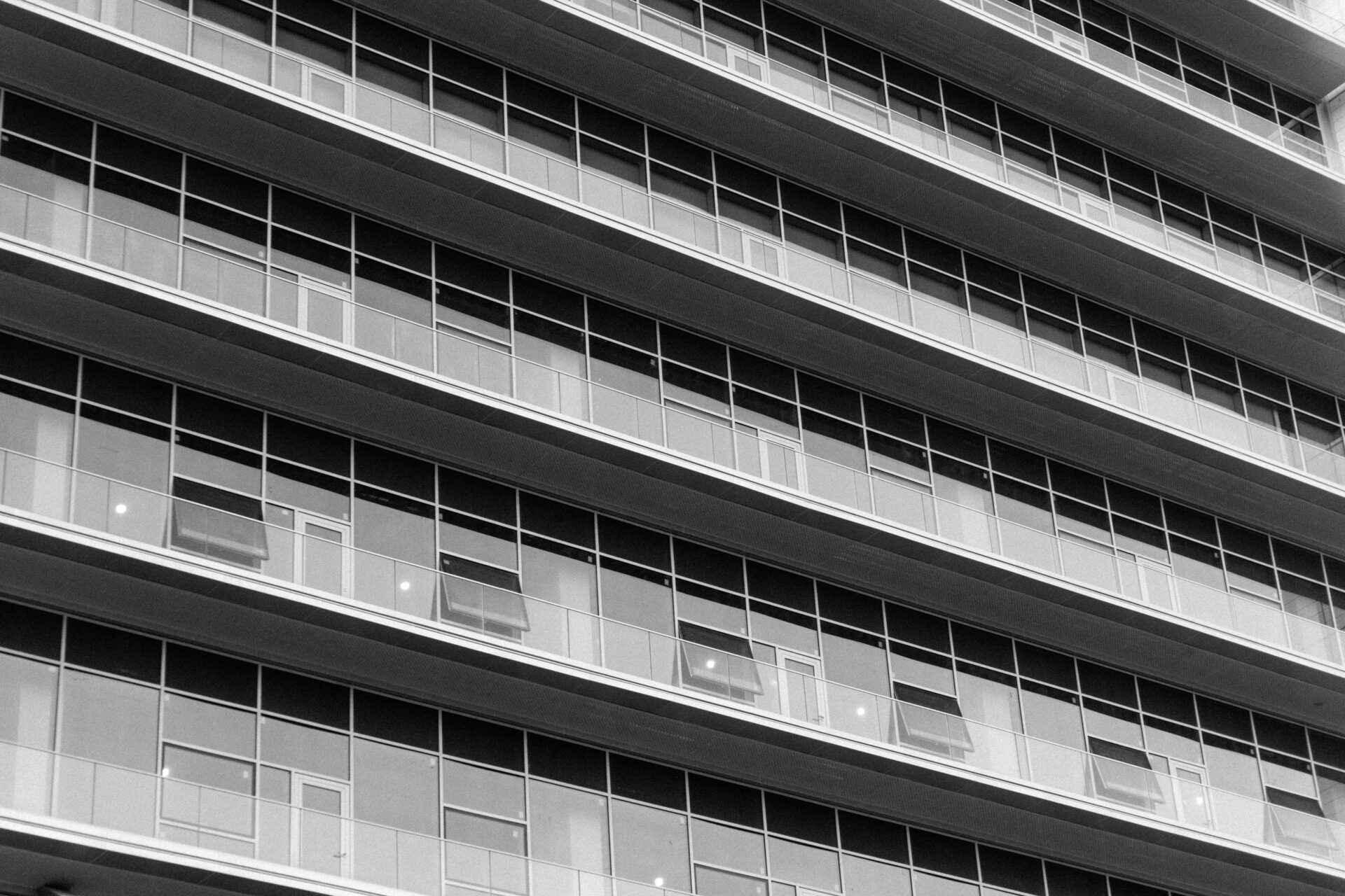 Schwarzweißfoto eines modernen Hochhauses mit Glasfenstern, die das Stadtbild widerspiegeln.