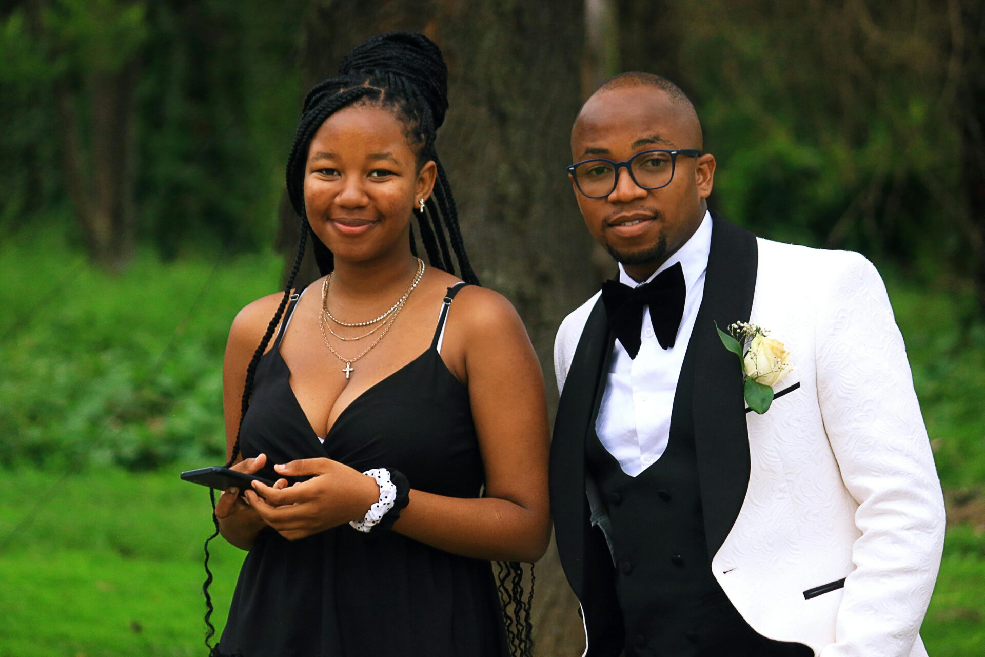 Ein elegant gekleidetes junges Paar lächelt bei einer Veranstaltung im Freien in Eswatini.