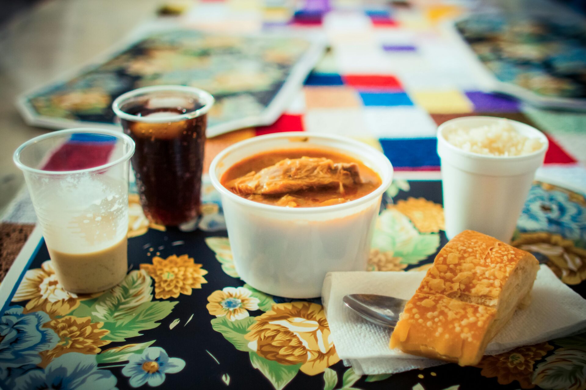 Eine lebendige Pr&Atilde;&curren;sentation einer k&Atilde;&para;stlichen Mahlzeit mit Suppe, Brot, Reis und Getr&Atilde;&curren;nken auf einer gemusterten Tischdecke.